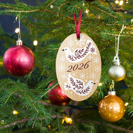 Dove wooden ornament hanging on a Christmas tree with red and gold baubles